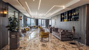 A modern interior with a marble floor, a sofa set, yellow chairs, and a plant. - Hotel & Resort Tre Fontane Luxury (Portici)