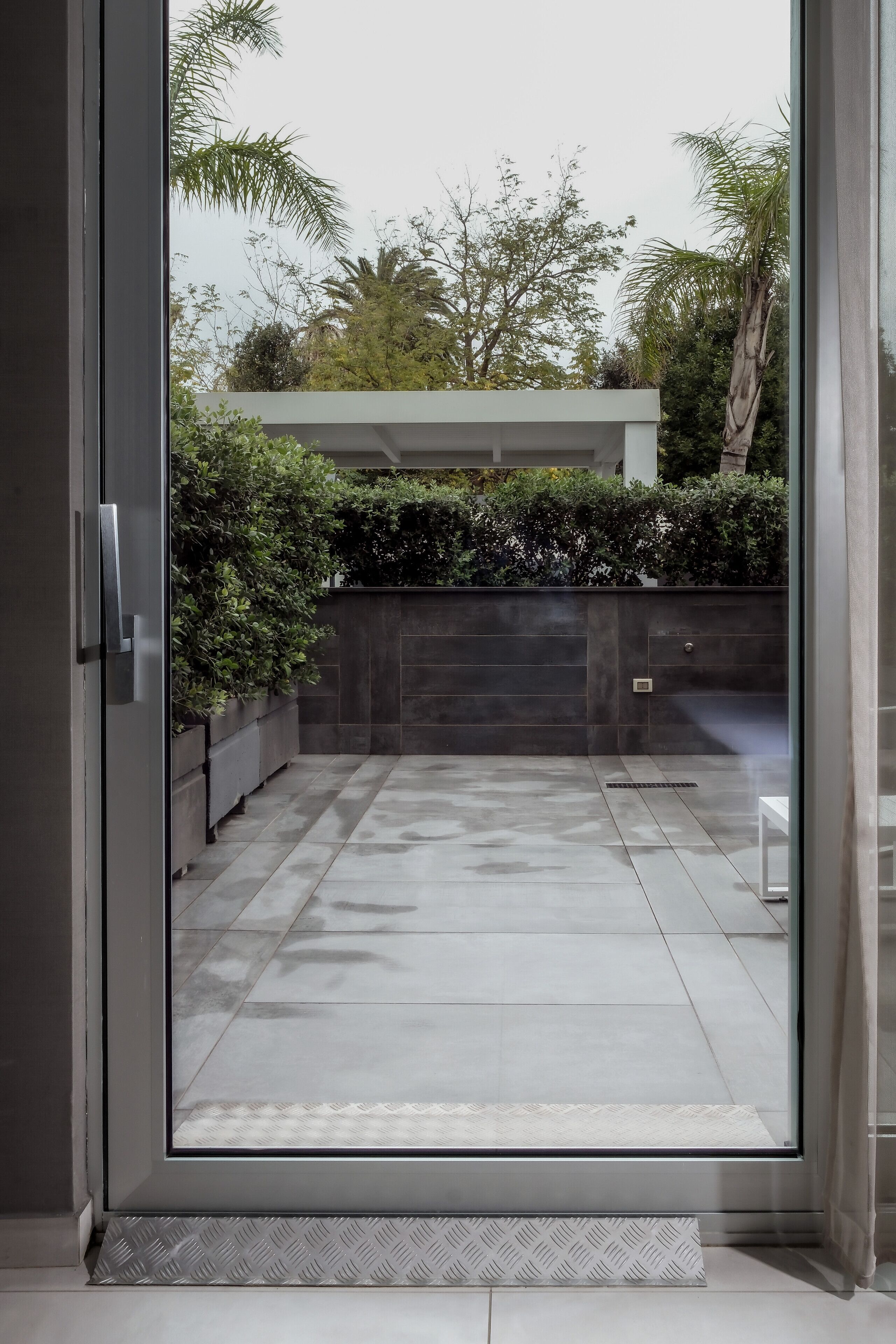 A modern, clean entrance with a glass door leading to a tiled patio area.