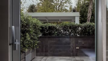 Un ingresso moderno e curato con una porta in vetro che si apre su un patio piastrellato.