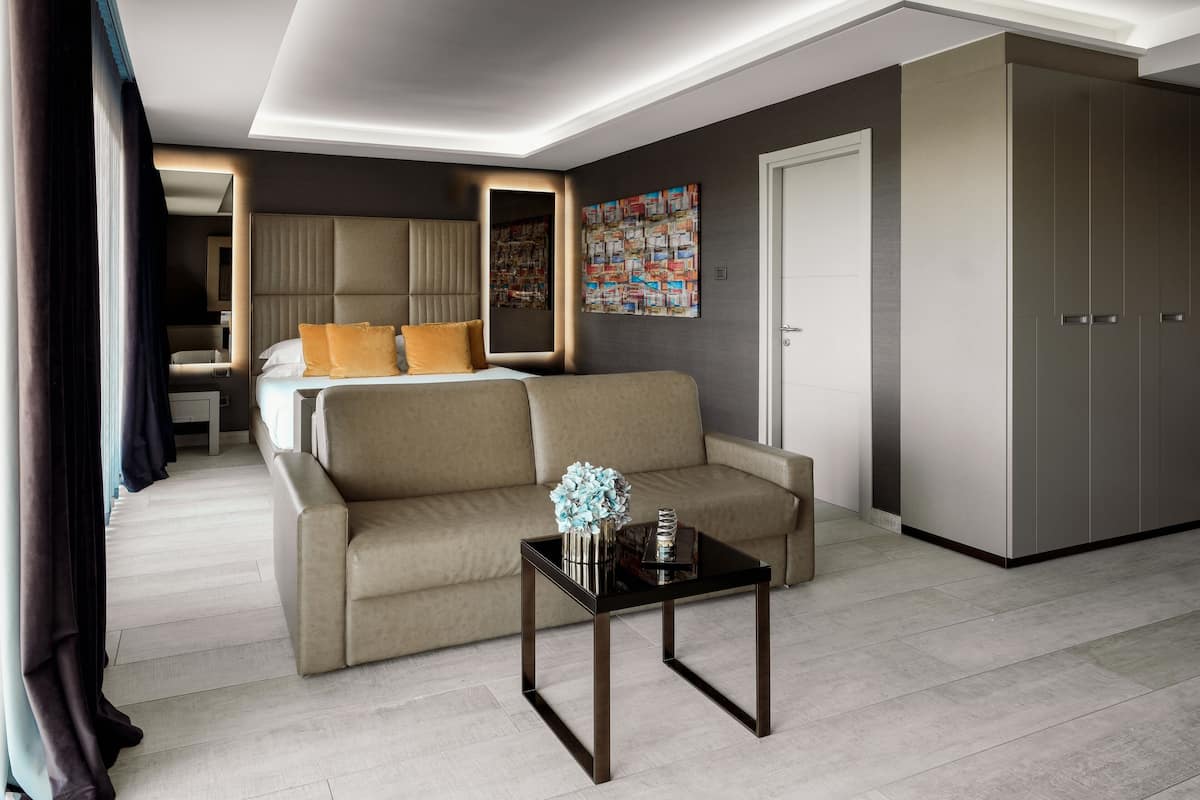 Ein modernes Hotelzimmer mit einem Bett, einer Couch, einem Couchtisch und einem Kleiderschrank.