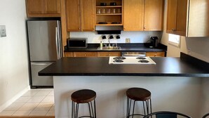 A modern kitchen with wooden cabinets, stainless steel appliances, and a black countertop.