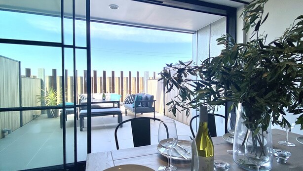 A dining area with a table set for two, a bottle of wine, and a potted plant. - Stunning 3 bedroom beachfront house with extensive sea views (Whitstable)
