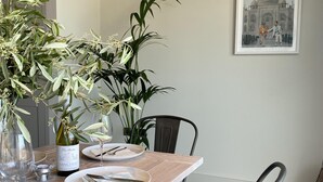 A dining table set with plates, cutlery, and a bottle of wine, surrounded by potted plants. - Stunning 3 bedroom beachfront house with extensive sea views (Whitstable)