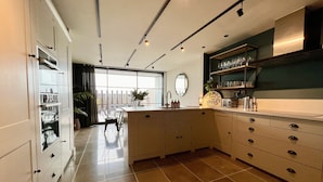 A modern kitchen with a large island, built-in cabinets, and a view to the outside. - Stunning 3 bedroom beachfront house with extensive sea views (Whitstable)