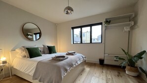 A bedroom with a bed, bedside table, mirror, window, and a potted plant. - Stunning 3 bedroom beachfront house with extensive sea views (Whitstable)