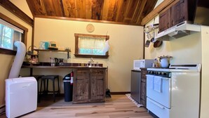 Eine Küche mit Holzausstattung, einem Herd, einem Kühlschrank und einem Fenster mit kariertem Vorhang.