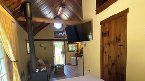 Ein Zimmer mit Holzboden, Kamin, Wandfernseher und einer großen Holztür.