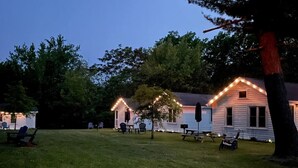 A cabin with a porch and string lights, surrounded by trees.