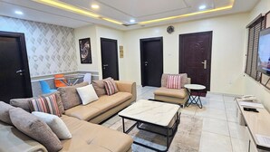 A living room with a sofa, a coffee table, a TV, and a small table with a phone and papers.