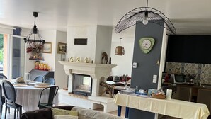 Un salon avec un canapé, un coin repas avec une table et des chaises, une cheminée et un coin cuisine équipé d’une télévision et d’un comptoir.