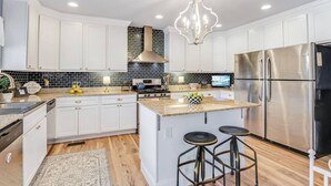 A modern kitchen with white cabinetry, a stainless steel refrigerator, a gas stove, and a chandelier. - BEST LOCATION+ON THE WATER+ROOM FOR EVERYONE! MM23 (Osage Beach)
