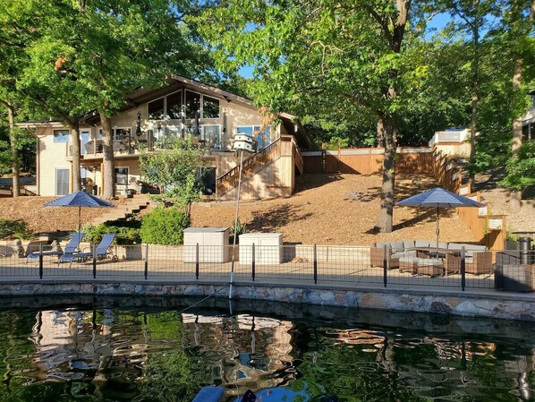 A house with a pool, a bridge, and outdoor furniture.