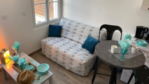 Een gezellige kamer met een gestreept sofa, een klein tafeltje met een dienblad en uitzicht door een raam.