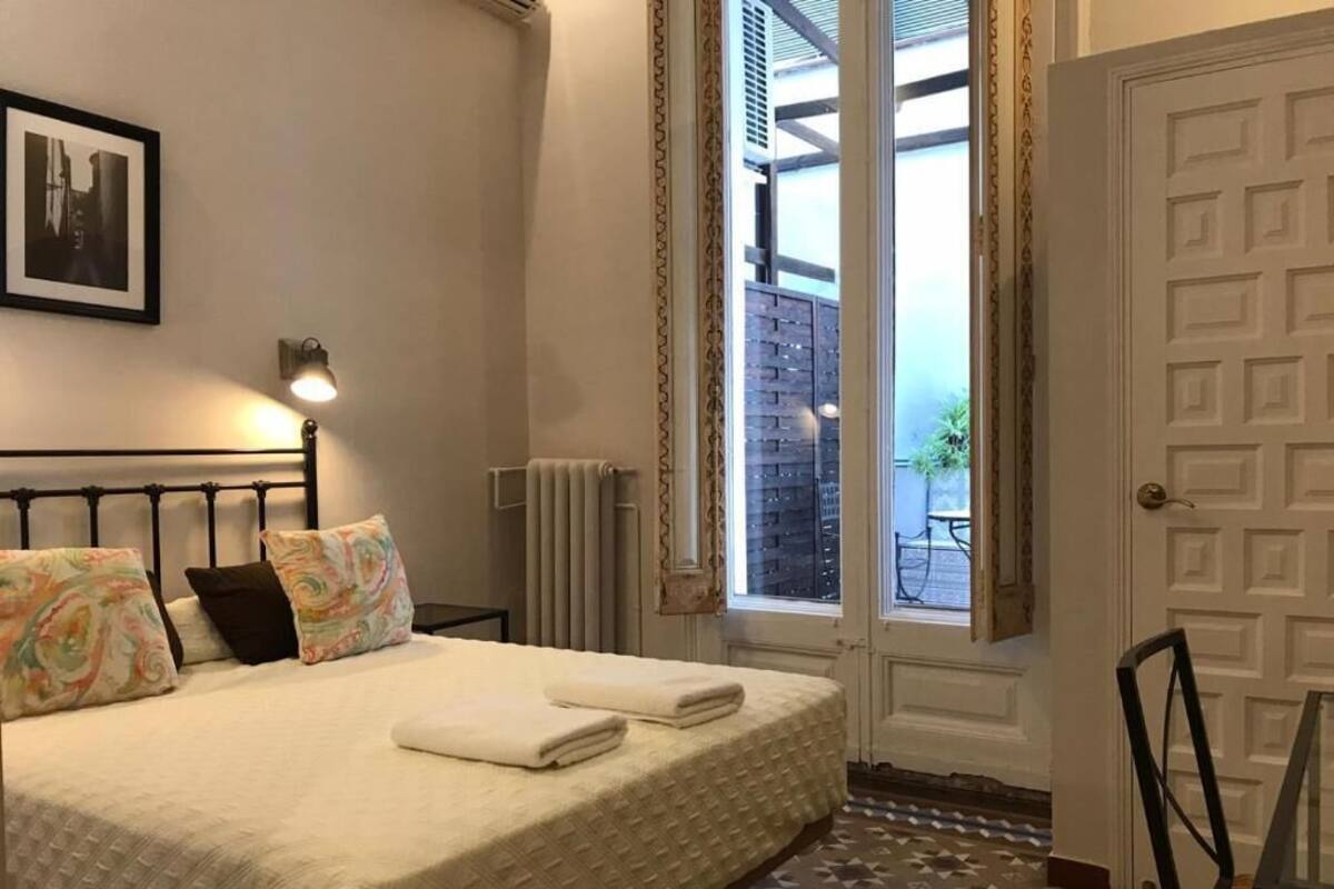 A bedroom with a bed, pillows, a radiator, a door, and a window.