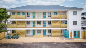A two-story motel with numbered balconies and a row of bicycles parked in front. - The Surf Shanty Motel (Dewey Beach)