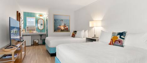 A hotel room with two beds, a desk with a computer, a TV, and a window with a view of the sea.