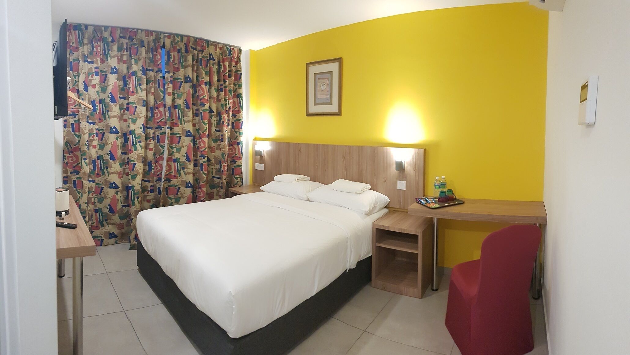 A hotel room with a bed, bedside tables, a desk, and a chair.