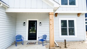A two-story house with a covered porch, a black door, and two blue chairs. - Modern New-Build w/ Screened Porch - Walk to Beach (Michigan City)