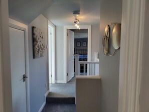Staircase leads to a beautifully appointed area with a door, artwork, and decorative wall piece.