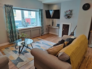 Relax in this stylish living room with a comfortable sofa, flat-screen TV, and cozy throw blanket.
