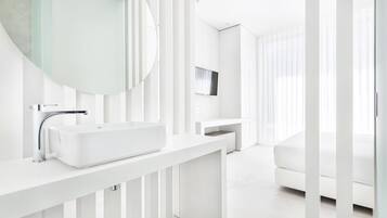 Un baño moderno y minimalista con un lavabo blanco grande, un espejo redondo y un grifo elegante.