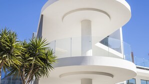Un edificio moderno con un diseño curvo y varios niveles, y barandillas de vidrio.
