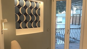 Ein modernes Wohnzimmer mit einem beige farbenen Sofa, einem runden Wandkunstwerk und einer Glasschiebetür, die zu einem Außenbereich führt.