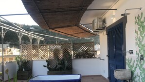 Eine Dachterrasse mit blauer Badewanne, einem Holzzapfen und einer Kakteepflanze.
