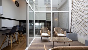 A modern kitchen with a dining area, featuring glass walls, wicker furniture, and a wooden floor. - Magnificent 4* apartment, ideally located (Biarritz)