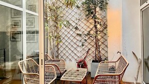 A small outdoor seating area with wicker chairs and a table, a potted plant, and a lattice wall with climbing plants. - Magnificent 4* apartment, ideally located (Biarritz)