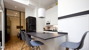 A modern kitchen with a central island, bar stools, and a coffee machine. - Magnificent 4* apartment, ideally located (Biarritz)