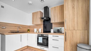 Una cocina moderna con armarios de madera, una campana extractora de acero inoxidable, horno empotrado y microondas.