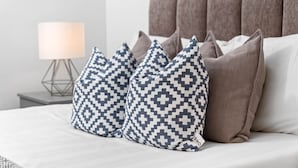Una cama con almohadas estampadas y un cabecero.