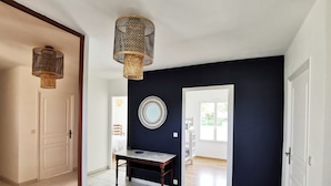 A hallway with a dark wall, a round mirror, and a table with a lamp.