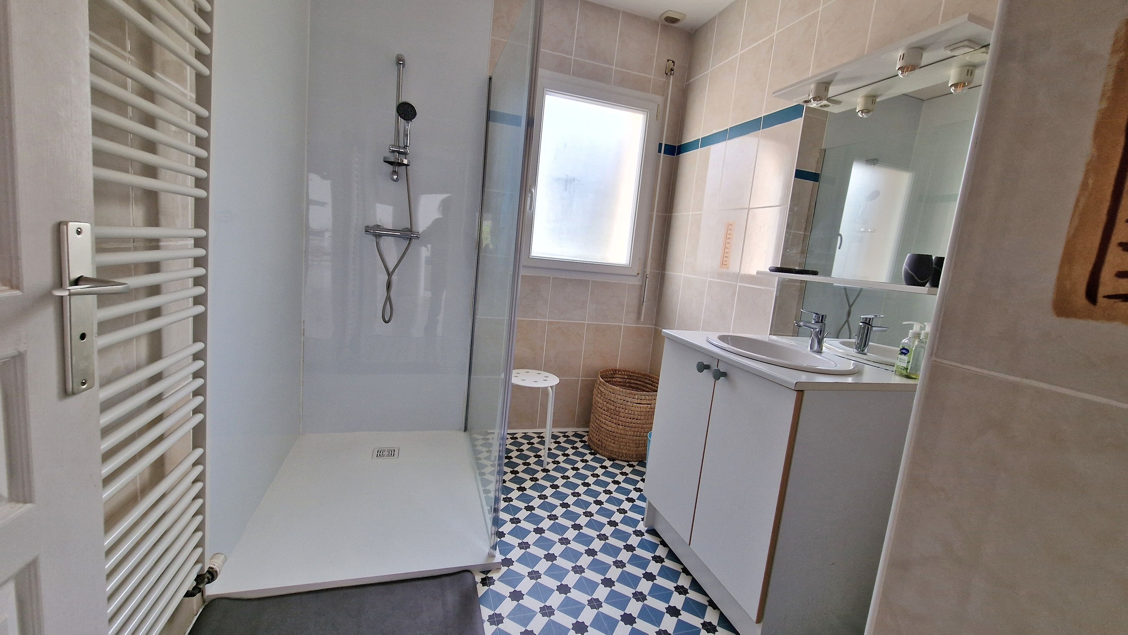 Une salle de bain avec une douche, un lavabo et une fenêtre.