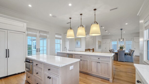 A spacious kitchen with a large island, wooden cabinets, and pendant lighting.
