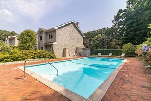 Relax by the pool surrounded by lush greenery and trees.