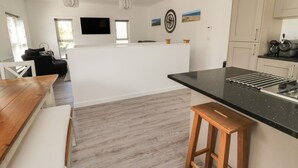 A modern kitchen with a black countertop, wooden stools, and a central island.
