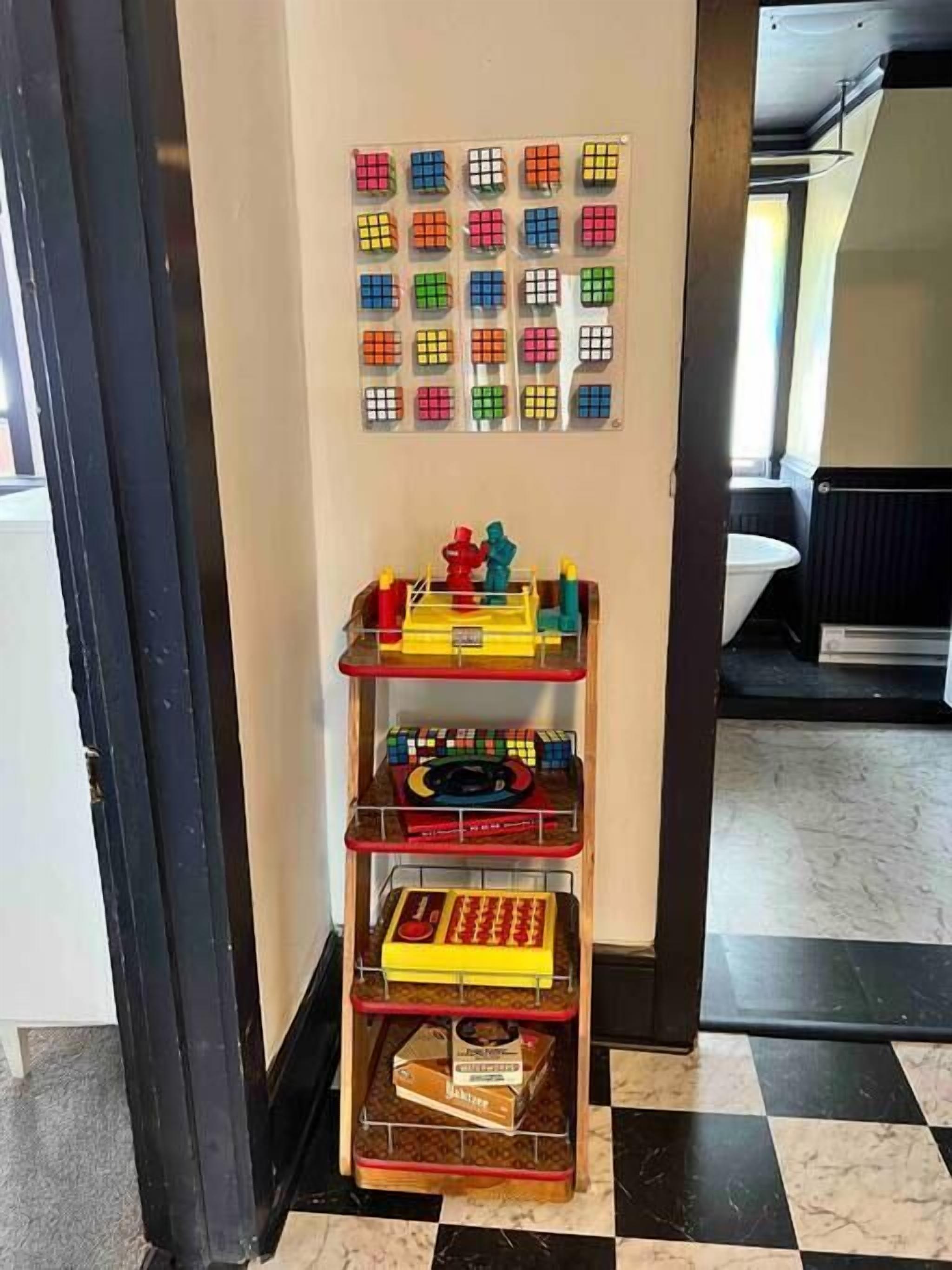 Una parete con un espositore di Cubi di Rubik e uno scaffale con giocattoli e giochi di logica.