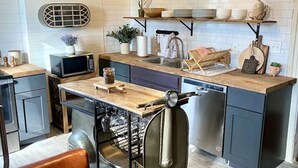 Una cocina moderna con una isla central, un área de comedor con una silla y un reloj en la pared.