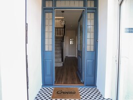 A blue door with a doormat reading "Croeso" leading to a staircase.