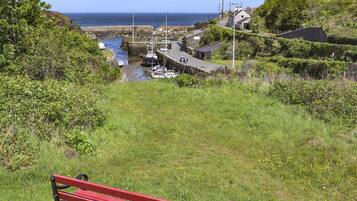 Un pueblo costero con un muelle, barcos y un banco rojo al frente.
