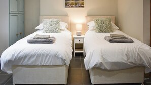 Habitación doble con dos camas, una mesita de noche, una lámpara y un cuadro colgado en la pared.