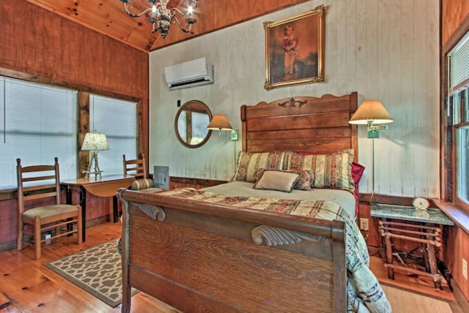 A wooden-themed bedroom with a bed, a desk, a chair, a mirror, and a lamp.