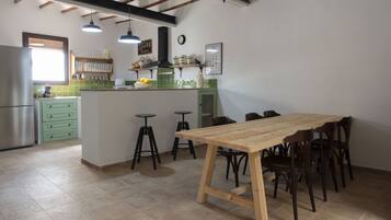 A kitchen with a wooden table and chairs, green cabinets, and a stainless steel refrigerator.