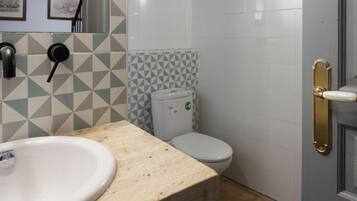 Un baño con lavamanos, inodoro y una puerta con pomo de latón.
