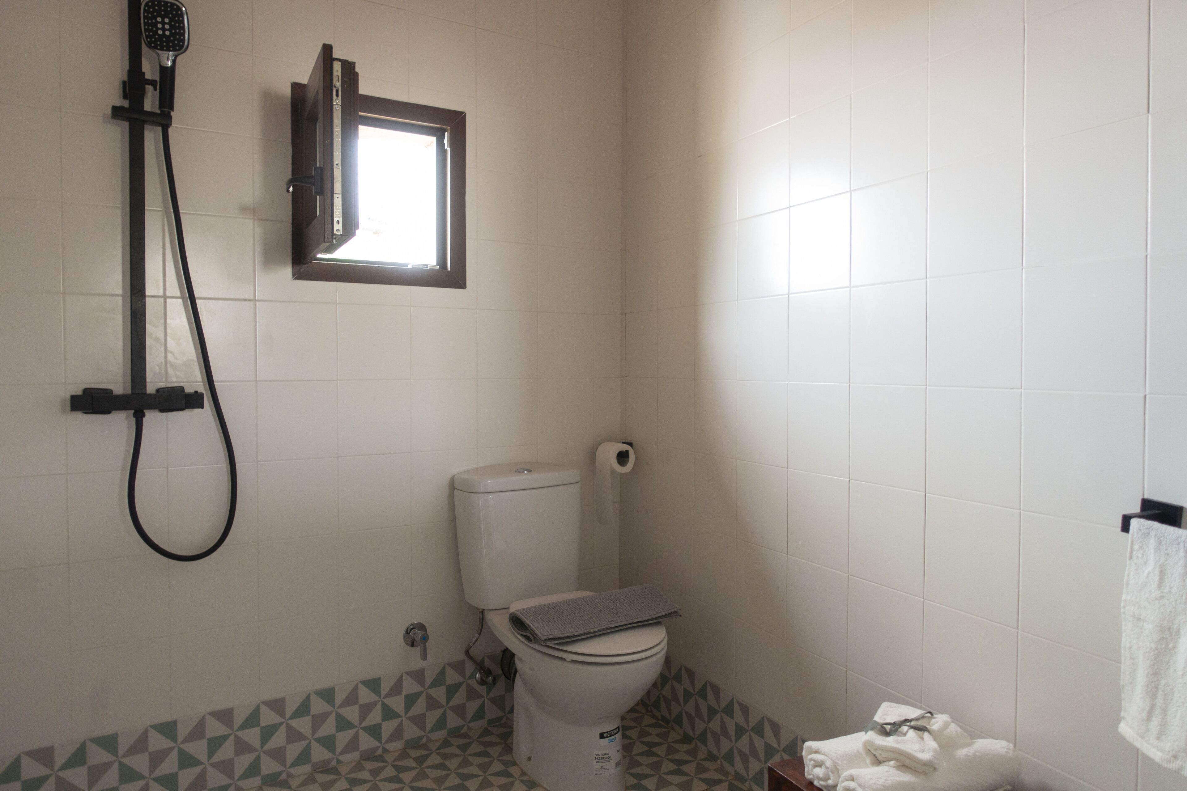 Un baño con inodoro, ducha y ventana.