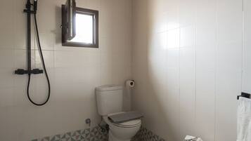 Un baño con inodoro, ducha y ventana.