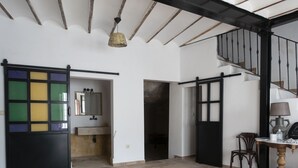 Une pièce spacieuse avec une grande porte coulissante, une table en bois avec une lampe et un escalier.