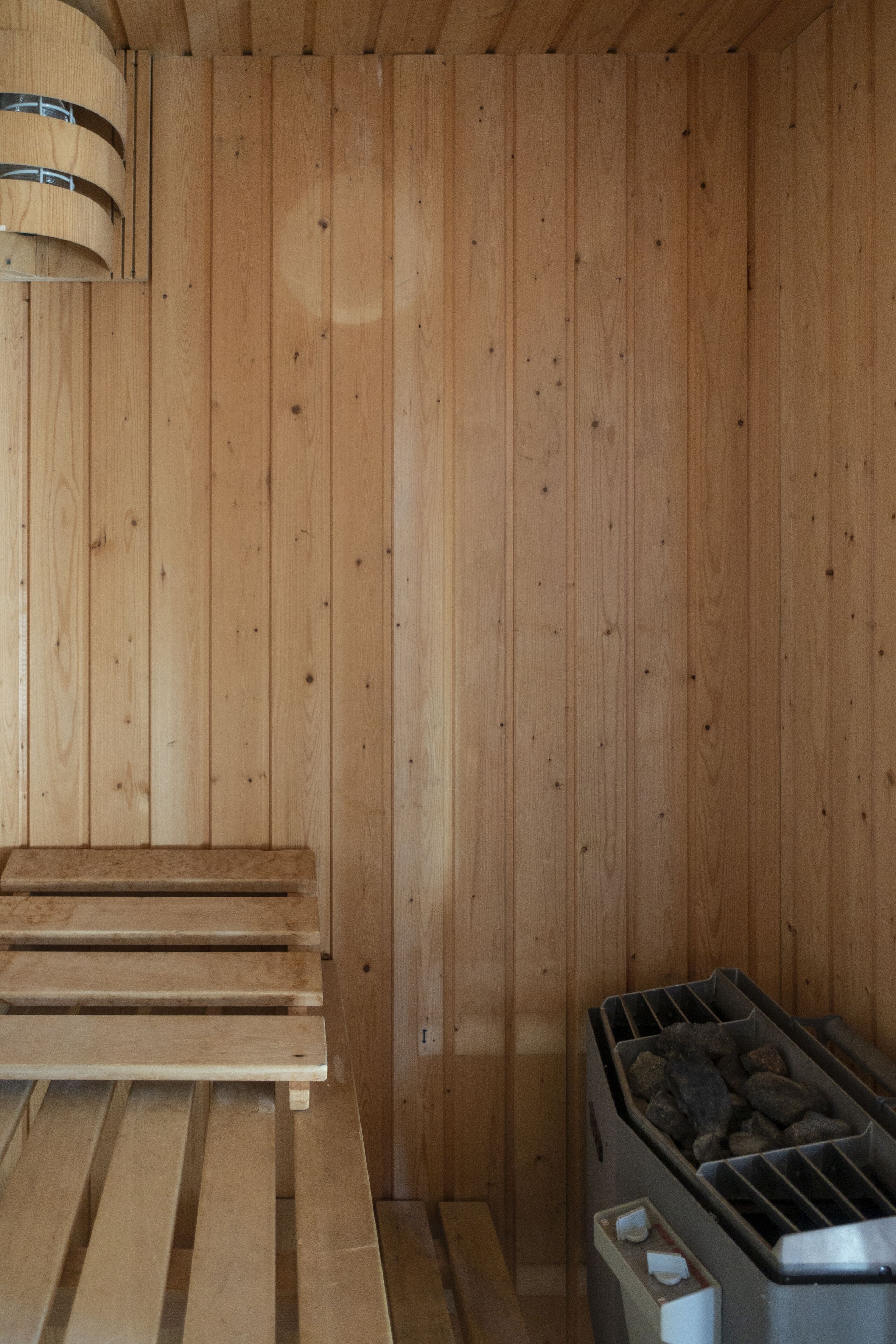 A wooden sauna room with benches and a sauna unit.